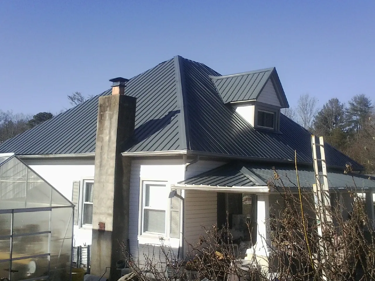 Dark blue standing seam metal roof on a white farmhouse with dormer — Slate & Tile Roof Repair by Roofing Brothers in Sauquoit