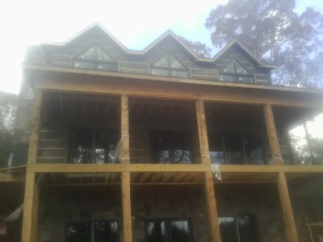 Dormers and porch framing on a large log home under construction — Roof Coating work by our crew in Sauquoit