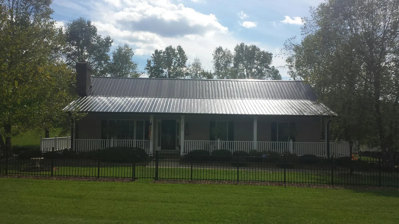 Gray metal roof on a brick ranch with a full width front porch — Gutter Guard Installation work by our crew in Sauquoit