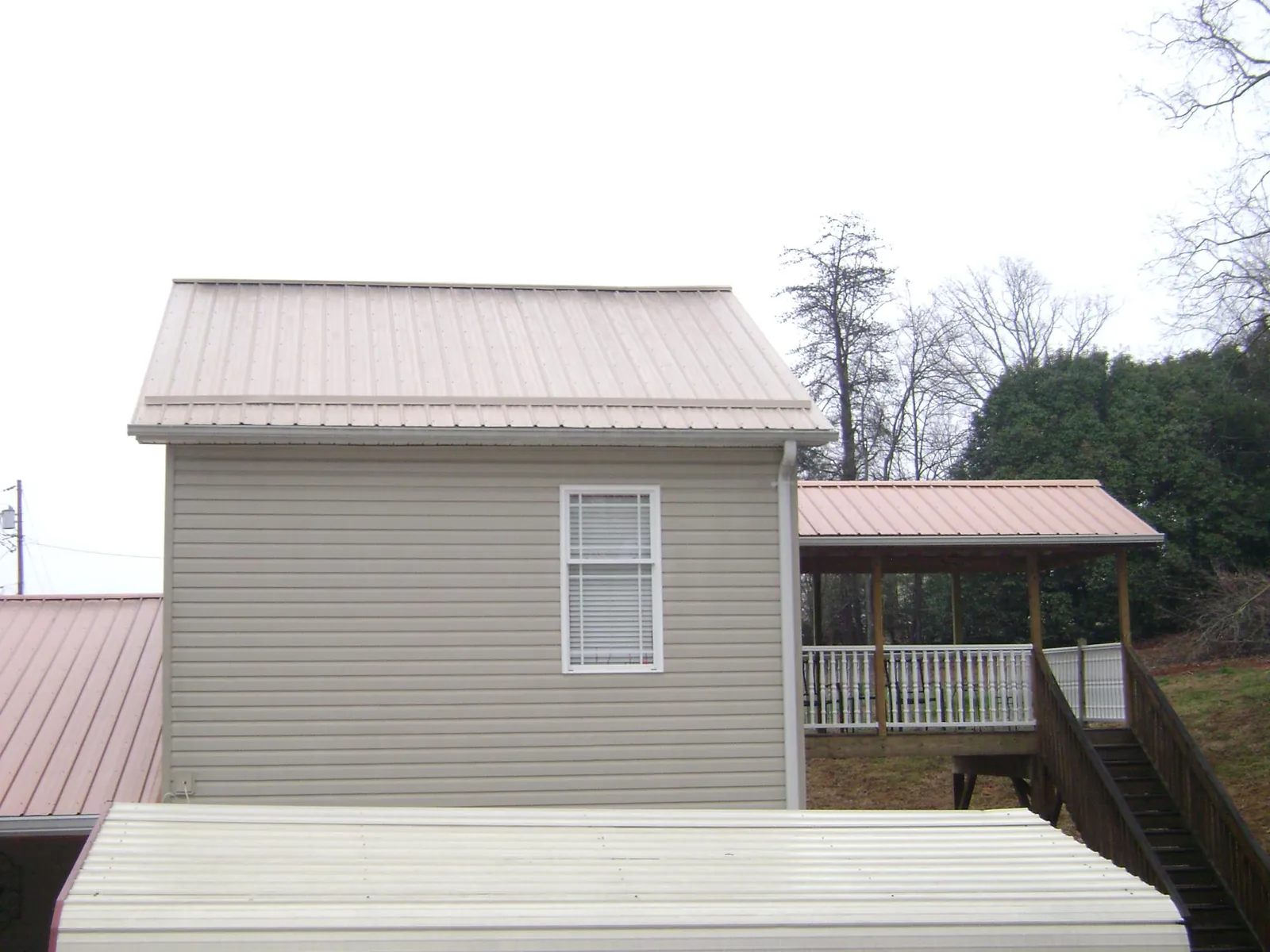 Tan metal roofs on a two story addition and attached porch, from a Roof Replacement job in Sauquoit