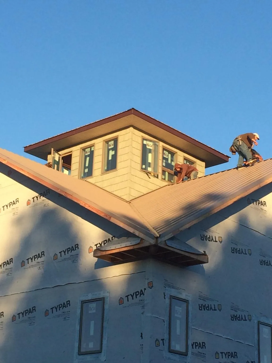 Roofers working around a rooftop cupola on a new metal roof at sunset — Roof Waterproofing in Sauquoit by Roofing Brothers
